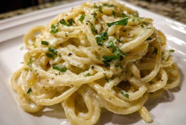Close-up of a serving of One-Pot Creamy White Bean Lemon Pasta, coated in a rich sauce and topped with fresh parsley.