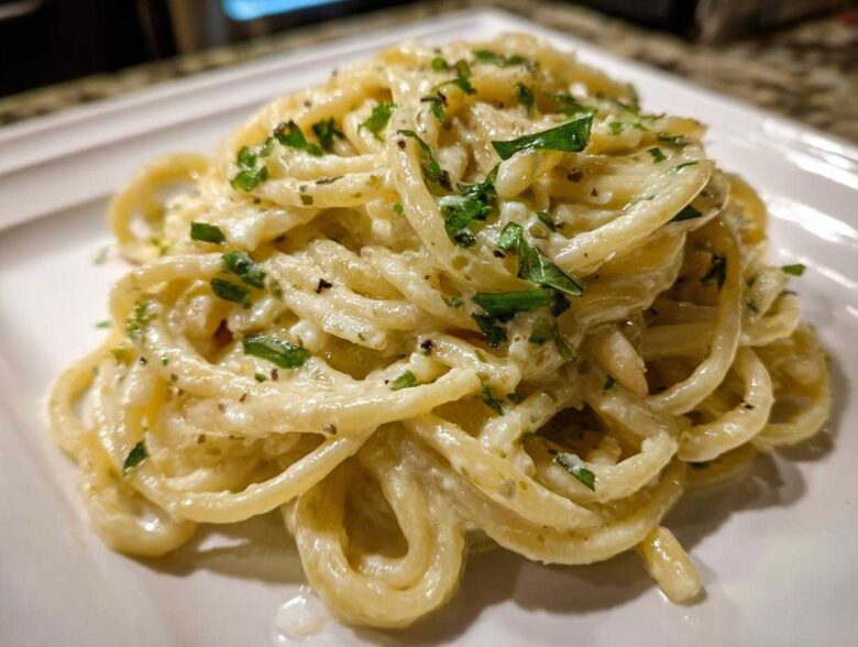 Close-up of a serving of One-Pot Creamy White Bean Lemon Pasta, coated in a rich sauce and topped with fresh parsley.