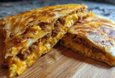 Two halves of a crispy Sheet Pan Breakfast Quesadillas cut open, showing melted cheese, scrambled eggs, and sausage filling.