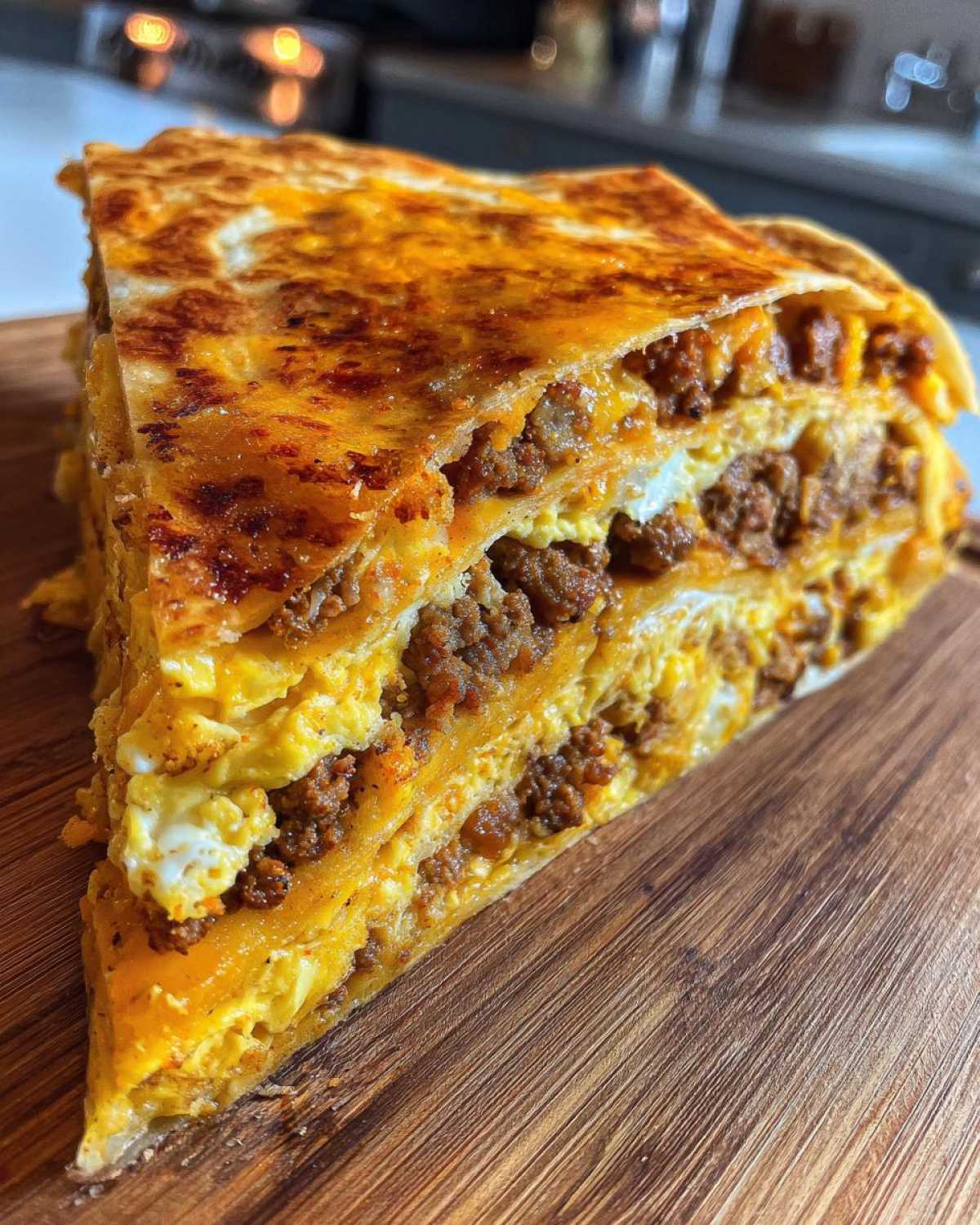 A thick, layered slice of Sheet Pan Breakfast Quesadillas showing melted cheese, scrambled eggs, and sausage filling.