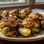 Golden brown pieces of Sheet Pan Garlic Butter Chicken and Brussels Sprouts served on a light plate.