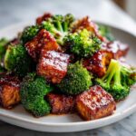 Close-up of crispy, glazed tofu cubes mixed with bright green broccoli florets, featuring Sheet Pan Sweet Chili Tofu.