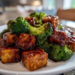 Close-up of glazed Sheet Pan Sweet Chili Tofu with bright green roasted broccoli florets on a white plate.