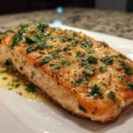 Close-up of a juicy, baked Garlic Butter Salmon fillet topped with minced garlic and fresh parsley.