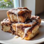 Close-up of stacked, gooey Banana Bread Batter Cinnamon Buns drizzled with white icing.