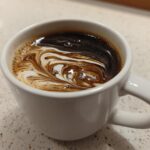 Close-up of coffee with cream swirling, illustrating the result of Vanilla Infusion for Quick Mornings.