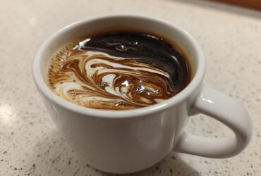 Close-up of coffee with cream swirling, illustrating the result of Vanilla Infusion for Quick Mornings.