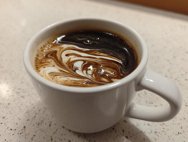 Close-up of coffee with cream swirling, illustrating the result of Vanilla Infusion for Quick Mornings.