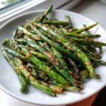Close-up of vibrant green beans coated in a savory, slightly charred glaze, ready to serve as Crack Green Beans.