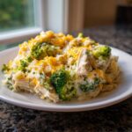 A close-up serving of Crockpot Broccoli Cheddar Chicken and Rice topped with melted cheddar cheese.
