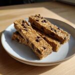 Four homemade chocolate chip bars stacked on a light blue plate, demonstrating Easy Homemade High-Protein Snack Bar Ideas.