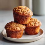 Three golden brown Oat Muffins Breakfast stacked slightly on a small ceramic plate.