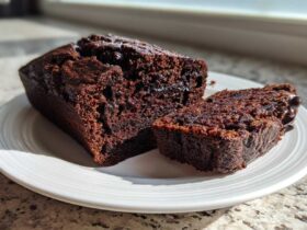 Close-up of a very moist chocolate zucchini bread loaf, partially sliced, showing its rich, dark crumb.