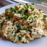 A close-up of creamy Cajun Chicken Alfredo Orzo Flavor served on a white plate and garnished with fresh parsley.