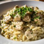 Close-up of creamy Cajun Chicken Alfredo Orzo Flavor topped with diced chicken and fresh parsley.