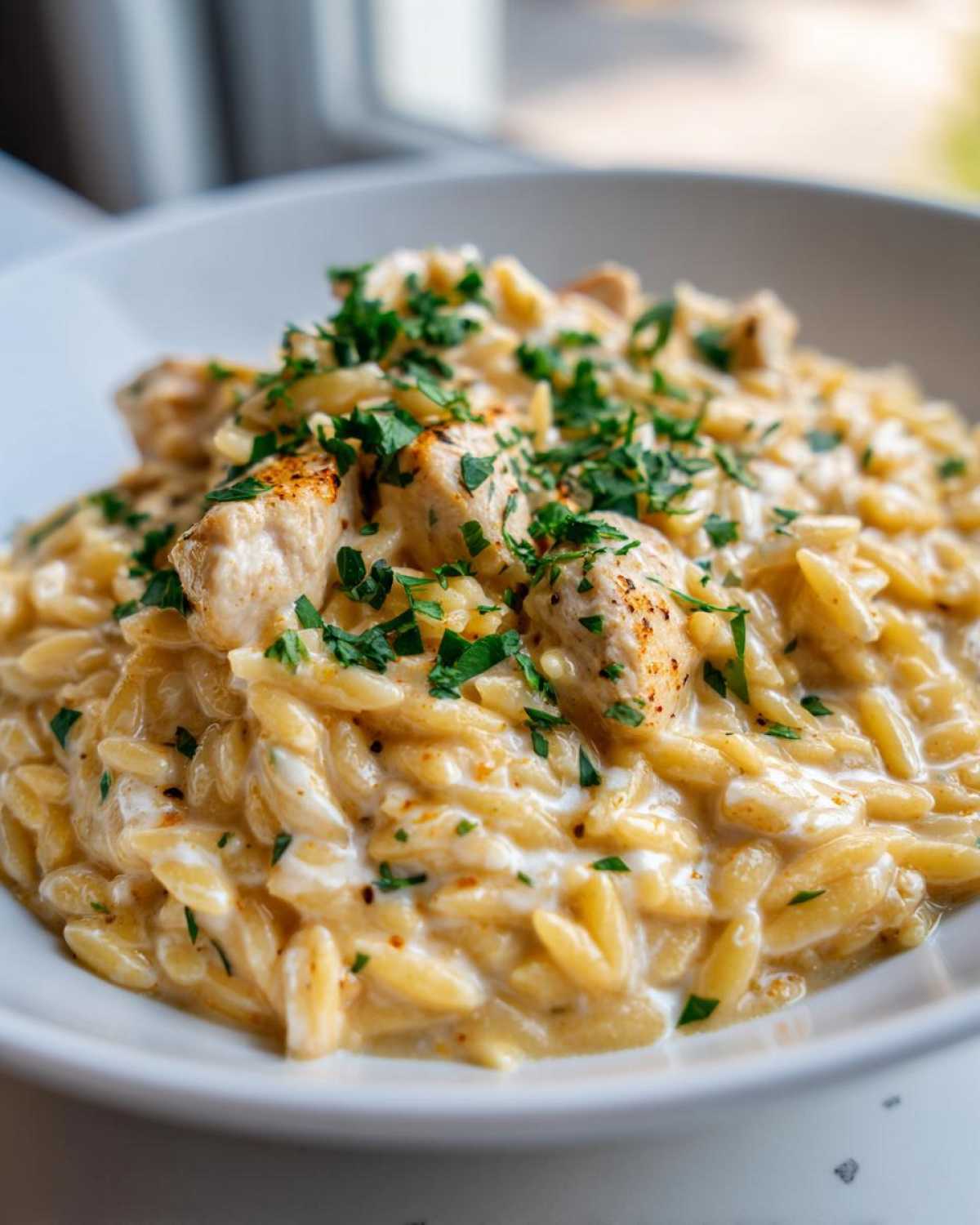 Close-up of creamy Cajun Chicken Alfredo Orzo Flavor topped with diced chicken and fresh parsley.
