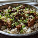 A close-up of delicious One-Skillet Fried Chicken Rice topped with browned chicken pieces and fresh green onions.