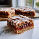 A square piece of Salted Caramel Pop Tart Bars with a thick caramel filling and white icing drizzle, sitting on a marble surface.