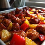 Close-up of glazed chicken pieces, pineapple chunks, and red peppers cooking in a sheet pan for Hawaiian Chicken Pineapple Teriyaki Glaze.