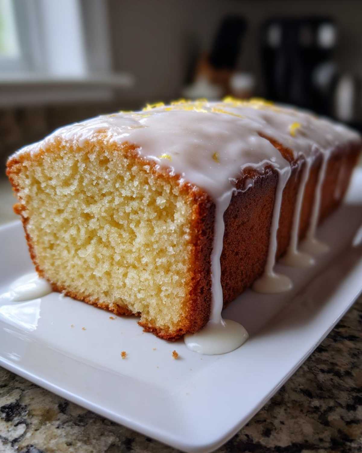 Close-up of a slice of Starbucks Copycat Lemon Loaf with thick white glaze dripping down the sides.